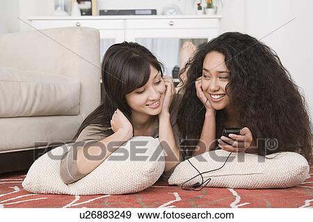 Young women listening to mp3 together View Large Photo Image Stock Photo - Young women listening to mp3 together. Fotosearch