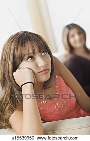 Stock Image - Angry daughter sitting with mother on sofa. Fotosearch