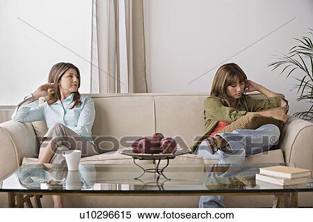 Stock Photography - Angry daughter sitting with mother on sofa. Fotosearch