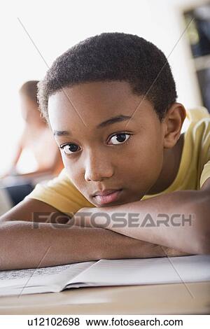Stock Photo - Bored schoolboy leaning on desk. Fotosearch