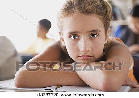 Stock Image - Bored schoolgirl leaning on desk. Fotosearch
