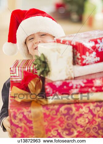 Stock Image - Boy (6-7) carrying christmas gifts. Fotosearch