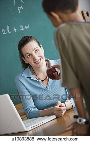 Stock Photo - Boy attempting to bribe teacher with apple. Fotosearch