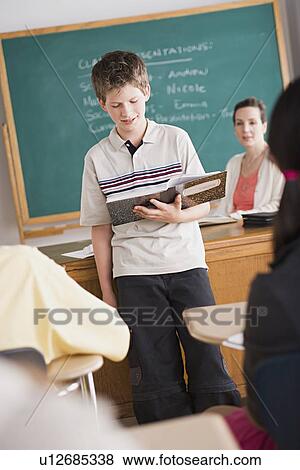 Stock Photo - boy reading from book in classroom. Fotosearch