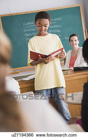 Stock Photograph - Boy reading from book in front of class. Fotosearch