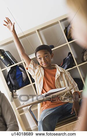 Stock Photo - Boy rising hand in classroom. Fotosearch