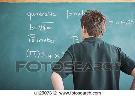 Boy standing in front of blackboard looking at mathematical formula View Large Photo Image Stock Image - Boy standing in front of blackboard looking at mathematical formula. Fotosearch