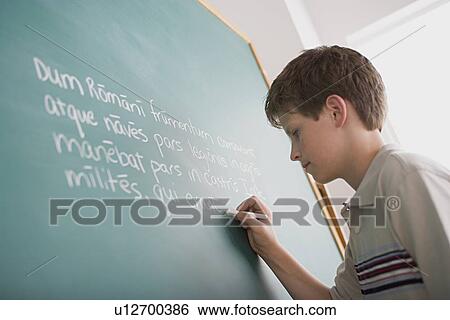 Stock Photograph - Boy writing Latin text on blackboard. Fotosearch