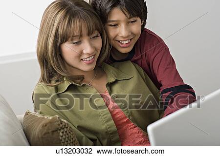 Brother and sister using laptop in living room View Large Photo Image Stock Image - Brother and sister using laptop in living room. Fotosearch