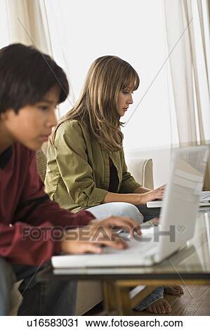 Brother and sister using laptops in living room View Large Photo Image Stock Image - Brother and sister using laptops in living room. Fotosearch