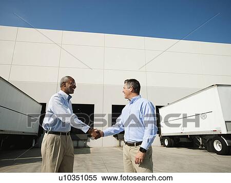 Business men shaking hands outside warehouse View Large Photo Image Stock Photography - Business men shaking hands outside warehouse. Fotosearch