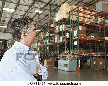 Businessman looking at goods in warehouse View Large Photo Image Picture - Businessman looking at goods in warehouse. Fotosearch