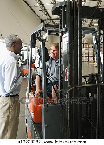 Businessman talking to forklift driver in warehouse View Large Photo Image Stock Image - Businessman talking to forklift driver in warehouse. Fotosearch