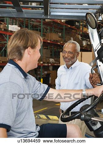 Businessman talking to forklift driver in warehouse View Large Photo Image Stock Photo - Businessman talking to forklift driver in warehouse. Fotosearch