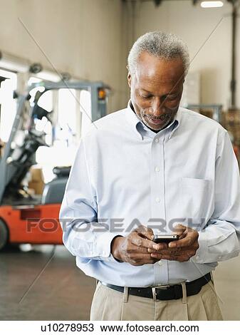 Businessman using phone in warehouse View Large Photo Image Stock Image - Businessman using phone in warehouse. Fotosearch