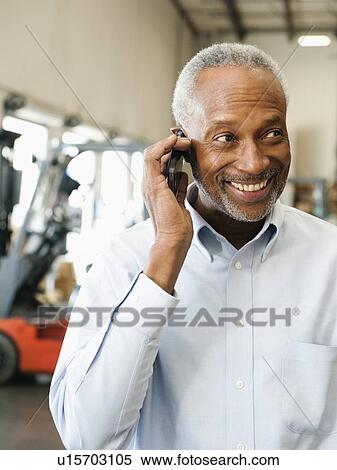 Businessman using phone in warehouse View Large Photo Image Stock Photography - Businessman using phone in warehouse. Fotosearch