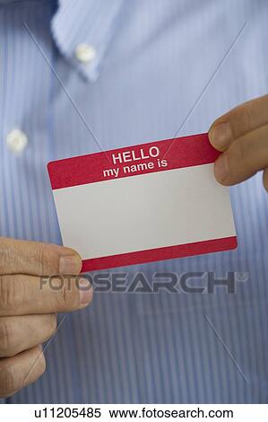 Stock Photography - Close up of businessman's hands holding blank name tag, studio shot. Fotosearch