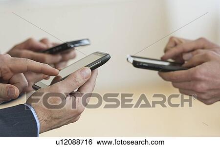 Stock Photograph - Close up of businessmen's hands holding PDA. Fotosearch