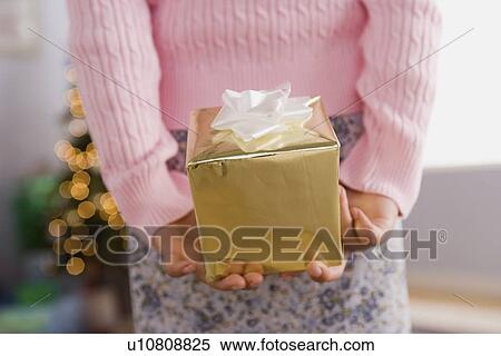 Close-up of girl holding Christmas present behind back, mid section View Large Photo Image Stock Photography - Close-up of girl holding Christmas present behind back, mid section. Fotosearch