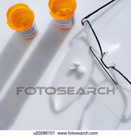 Stock Image - Close up of glasses and pills on white background, studio shot. Fotosearch