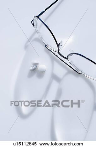 Stock Photography - Close up of glasses and pills on white background, studio shot. Fotosearch