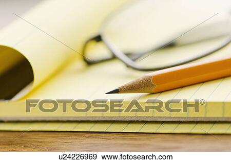 Stock Photo - Close up of glasses, notebook and pencil, studio shot. Fotosearch