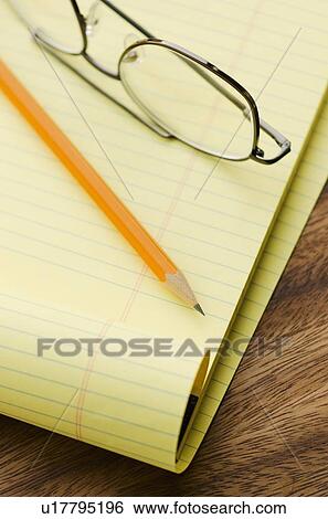 Stock Photograph - Close up of glasses, notebook and pencil, studio shot. Fotosearch