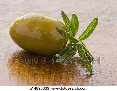 Stock Image - Close-up of green olive with rosemary, studio shot. Fotosearch