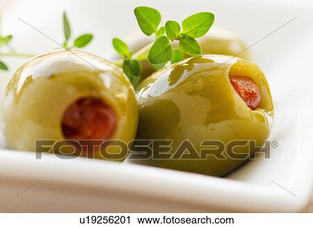 Stock Image - Close-up of green olives stuffed with pimento, studio shot. Fotosearch