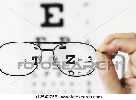 Close up of hand holding glasses above eye chart, studio shot View Large Photo Image Stock Photography - Close up of hand holding glasses above eye chart, studio shot. Fotosearch