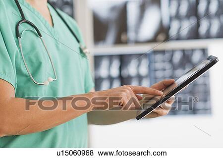 Stock Photo - Close up of male doctor using digital tablet. Fotosearch