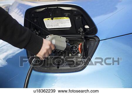 Stock Photo - Close-up of man charging electric car. Fotosearch