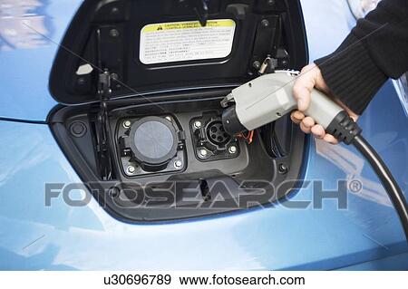 Close-up of man charging electric car View Large Photo Image Stock Photo - Close-up of man charging electric car. Fotosearch