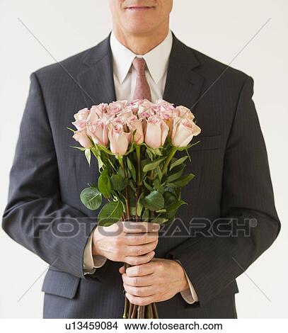 Close up of man in suit holding bouquet of roses, studio shot View Large Photo Image Picture - Close up of man in suit holding bouquet of roses, studio shot. Fotosearch