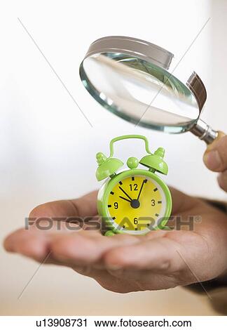 Close up of man's hand holding alarm clock and magnifying glass, studio shot View Large Photo Image Stock Image - Close up of man's hand holding alarm clock and magnifying glass, studio shot. Fotosearch