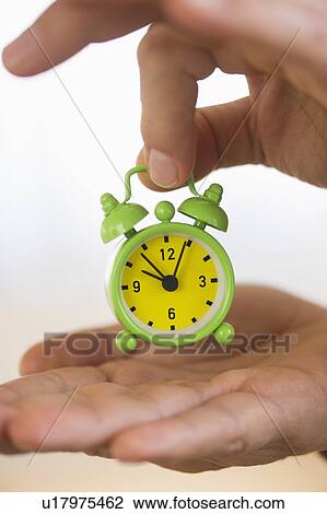 Close up of man's hand holding alarm clock, studio shot View Large Photo Image Stock Image - Close up of man's hand holding alarm clock, studio shot. Fotosearch
