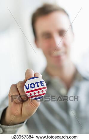 Picture - Close up of man's hand holding vote button. Fotosearch