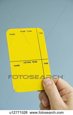 Stock Photograph - Close up of man's hand showing yellow card, studio shot. Fotosearch