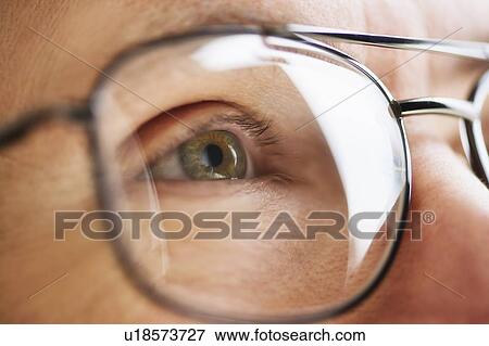 Stock Photo - Close up of men's eye looking through glasses. Fotosearch