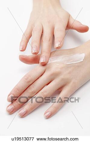 Stock Photo - Close up of woman's hands applying moisturizer, studio shot. Fotosearch