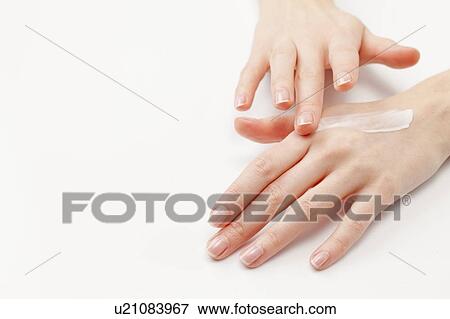 Stock Photo - Close up of woman's hands applying moisturizer, studio shot. Fotosearch