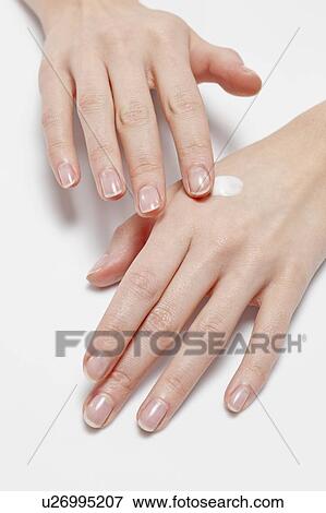 Stock Photo - Close up of woman's hands applying moisturizer, studio shot. Fotosearch
