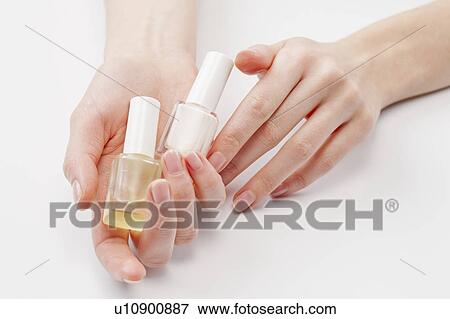 Stock Photo - Close up of woman's hands holding nail polish, studio shot. Fotosearch