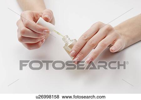 Stock Photo - Close up of woman's hands holding nail polish, studio shot. Fotosearch