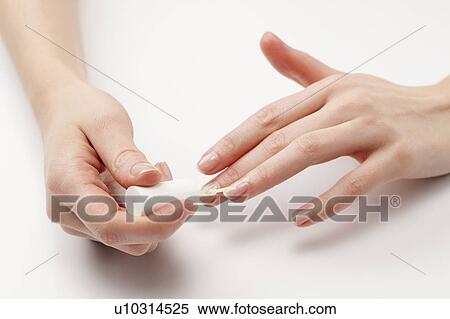 Stock Photography - Close up of woman's hands painting fingernails, studio shot. Fotosearch