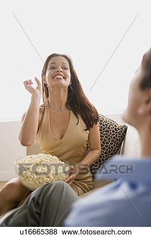 Couple at sofa, woman holding bowl full of popcorn View Large Photo Image Stock Photo - Couple at sofa, woman holding bowl full of popcorn. Fotosearch