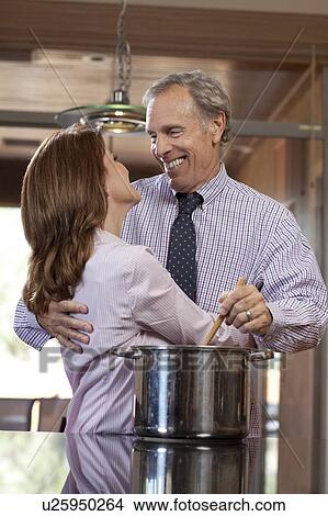 Couple embracing while cooking dinner View Large Photo Image Picture - Couple embracing while cooking dinner. Fotosearch