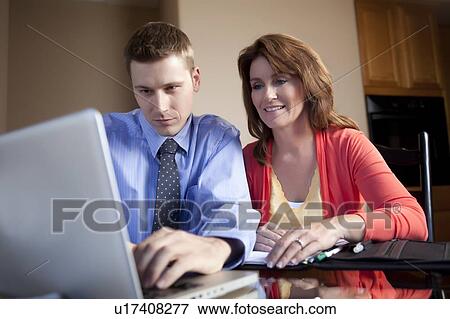 Couple looking at laptop View Large Photo Image Stock Photo - Couple looking at laptop. Fotosearch