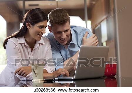 Couple looking at laptop View Large Photo Image Stock Photograph - Couple looking at laptop. Fotosearch