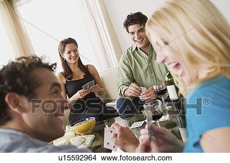Picture - Couples on sofa at home party playing cards. Fotosearch